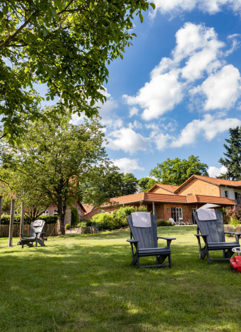 Zwei Sonnenstühle stehen unter einem strahlend blauen Himmel auf einer Wiese vor dem Landhotel