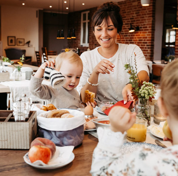Eine Mutter und ihr Sohn sitzen lachend am Tisch und essen ihr Frühstück.