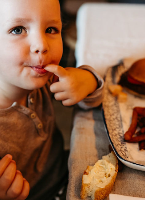 Junge mit Finger im Mund beim Mittagessen