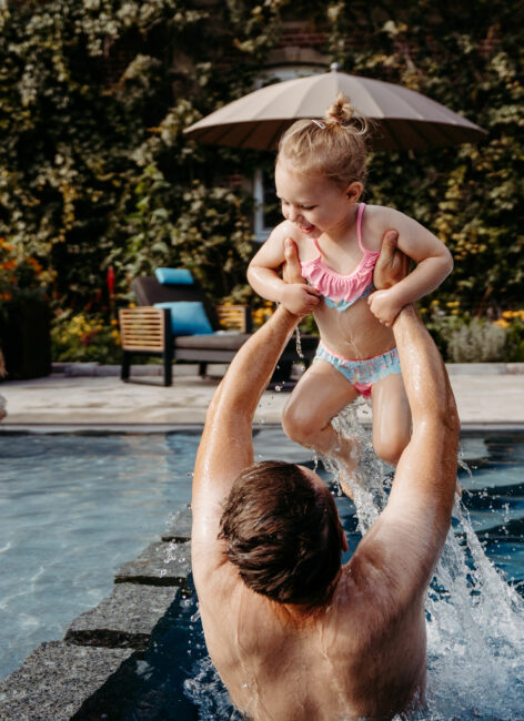Vater hebt Tochter im Pool hoch