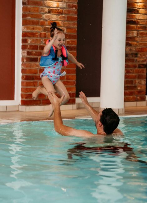 Ein Mädchen springt zu ihrem Vater in dem Pool während des All Inclusive Familienurlaubs