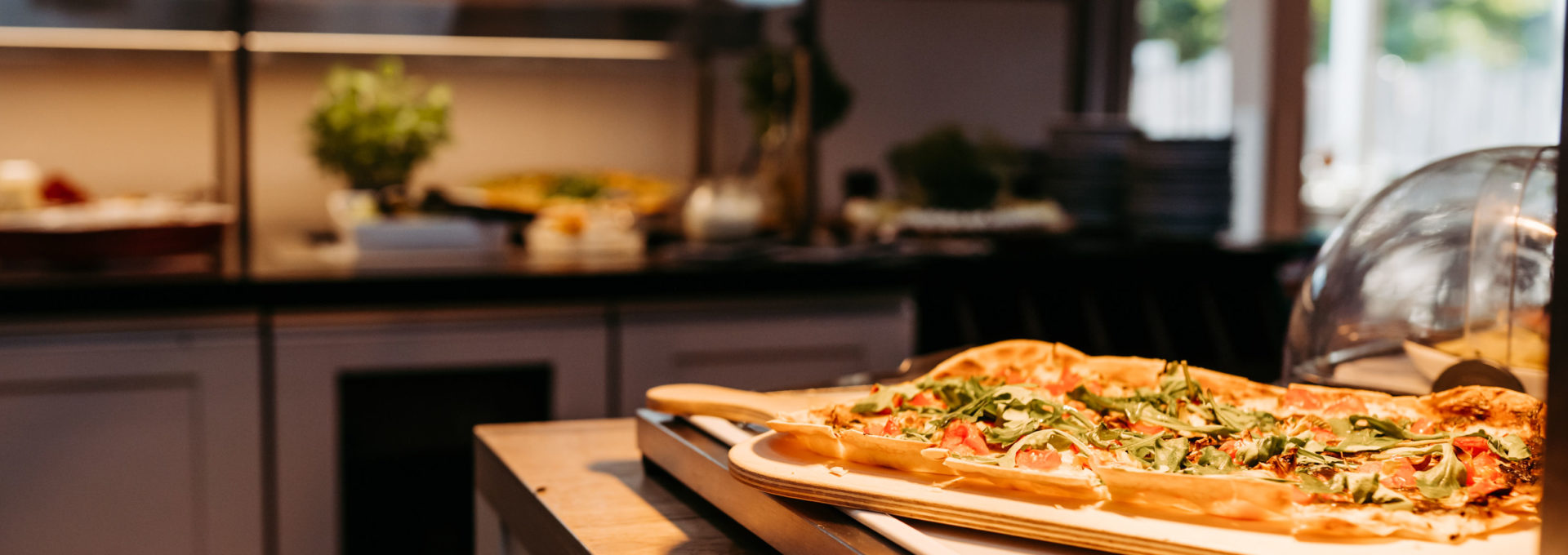 Detailaufnahme Flammkuchen mit Tomate und Rucola am Abendbuffet.