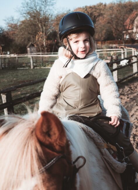Kleines Mädchen sitzt auf einem Pferd beim all inclusive Familienurlaub