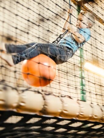 Ein kleiner Junge schwingt an einem Seil in der Spielscheunen beim All inclusive Familienurlaub