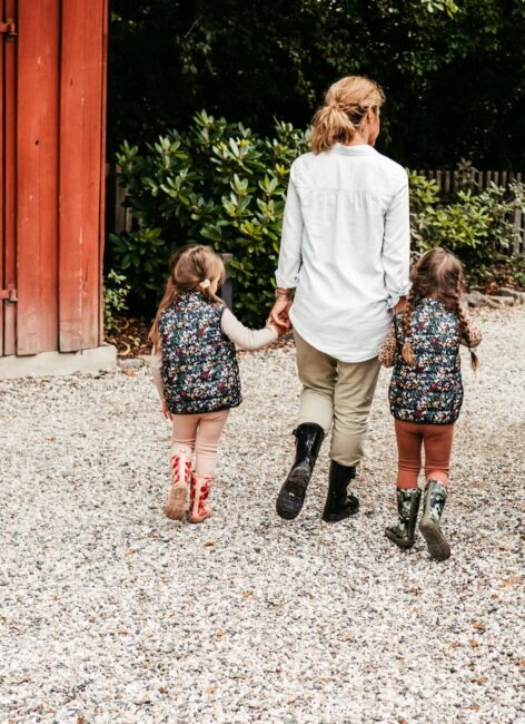 Eine Mutter spaziert mit ihren beiden Töchtern über einen Kiesweg