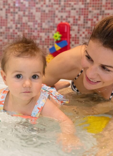 Junge mit mit ihrer kleinen Tochter im Planschbecken beim all inclusive Familienurlaub