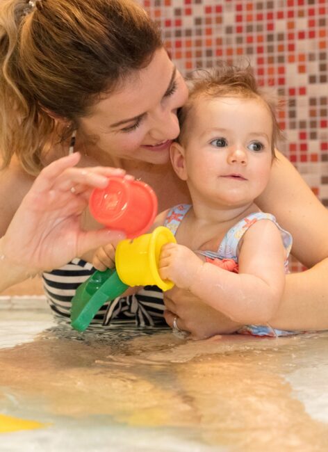 Junge Mutter spielt mit ihrem Kleinkind im Planschbecken beim all inclusive Familienurlaub in Niedersachsen