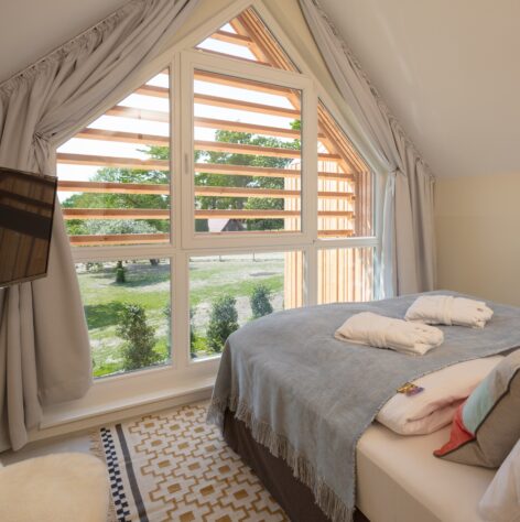 Bett auf einem gemusterten Teppich mit Blick aus einem großem Fenster