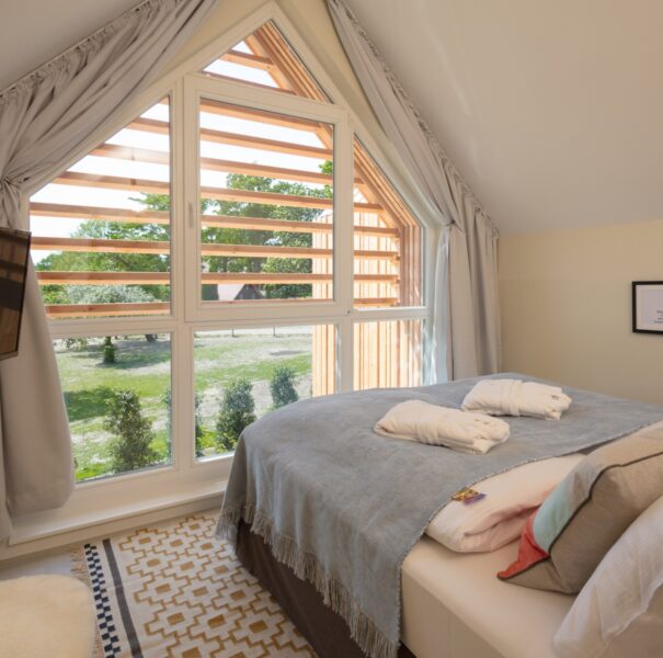 Einblick in das Schlafzimmer im Familienhotel in Niedersachsen mit großer Fensterfront und Bademänteln auf dem Bett