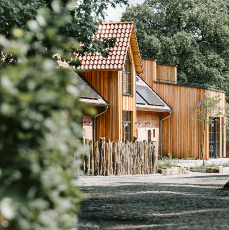 Blick auf die neue schöne Scheune des Landhauses mit edler Holzfassade und einem Holzzaun.