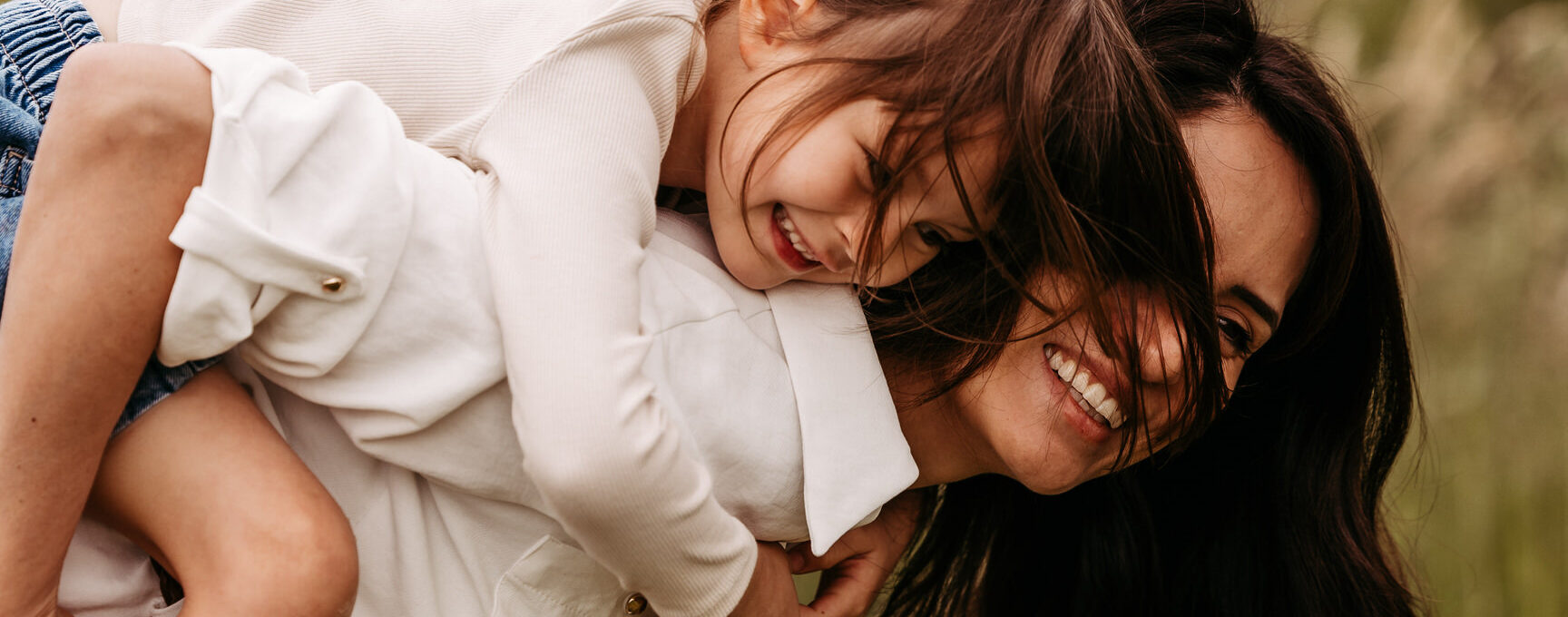 Mutter nimmt Tochter Huckepack und lachen zusammen
