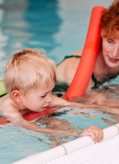 Schwimmlehrerin mit Junge am Beckenrand