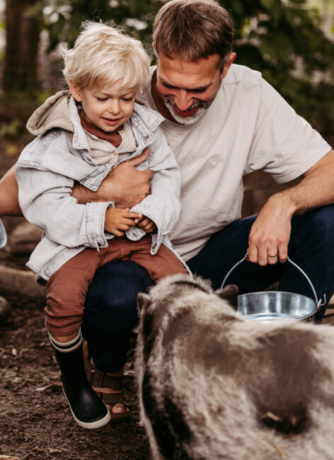 Junge mit Vater beim Tiere füttern, Hoftiere