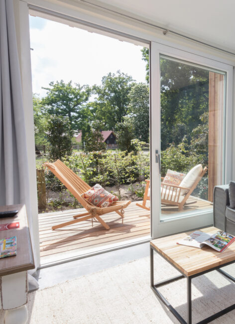 Blick auf die Terrasse mit Holzstühlen und Blick ins Grüne im Familienhotel mit Bauernhof