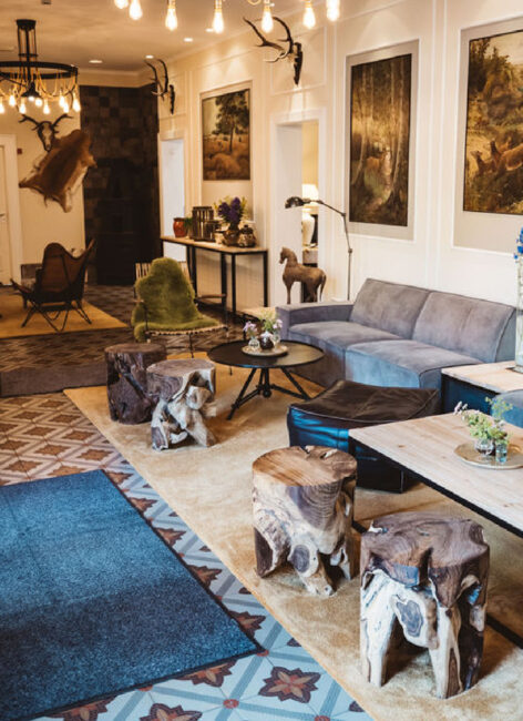 Charmante Lobby im Landhaus Averbeck mit Holzhockern aus Baumstämmen, Jagdgemälden und gemütlichen Sofas