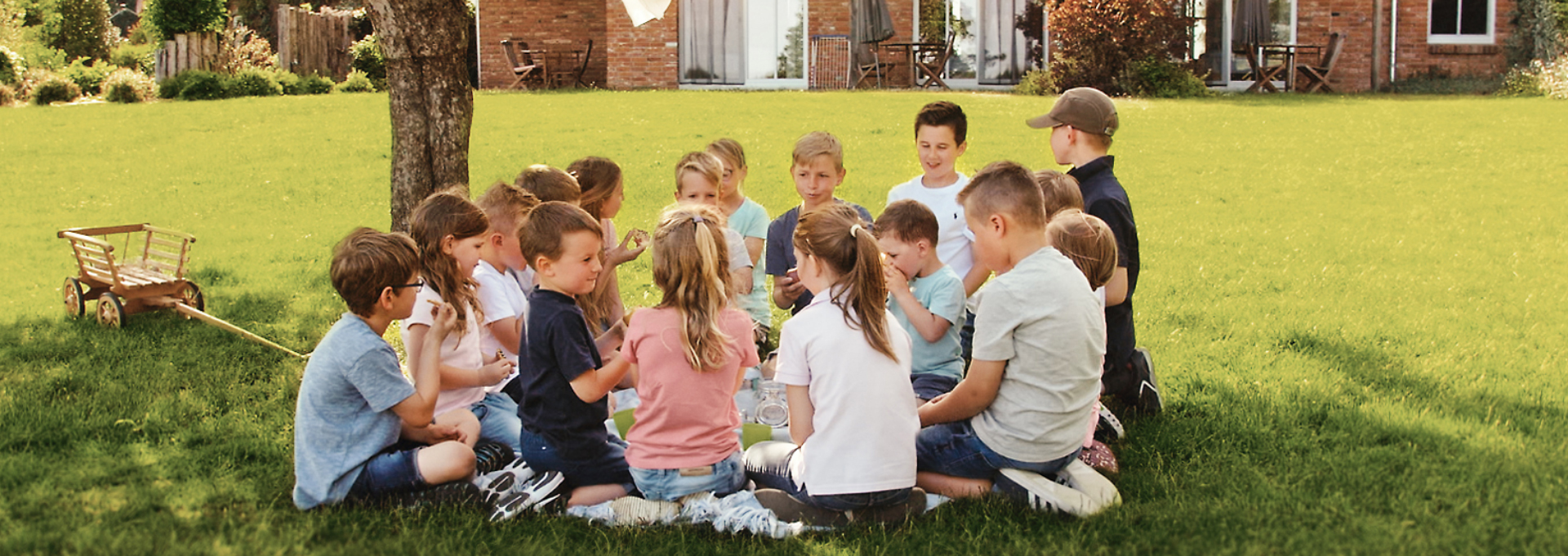Viele Kinder sitzen im Kreis auf einer Wiese im Landhaus Averbeck