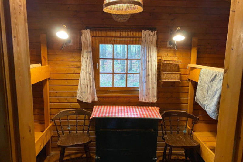 Rustikales Schlafzimmer in der Jagdhütte mit einem Tisch und zwei Stühlen
