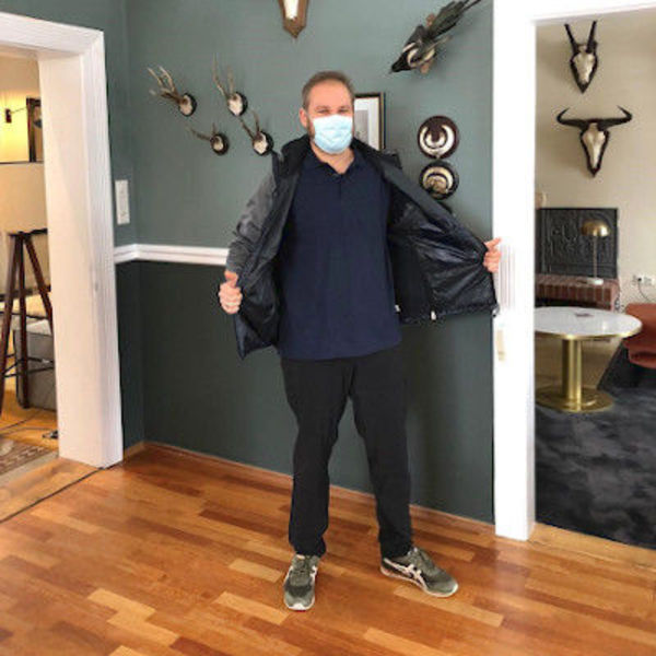 Mitarbeiter des Landhaus Averbeck trägt eine medizinische Maske und öffnet seine Jacke